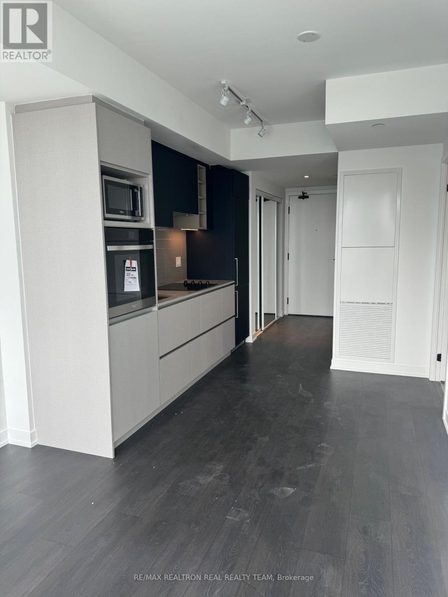 A modern kitchen with dark wood floors and white cabinets.