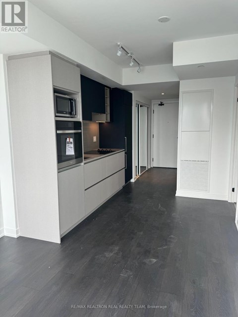 A modern kitchen with dark wood floors and white cabinets.