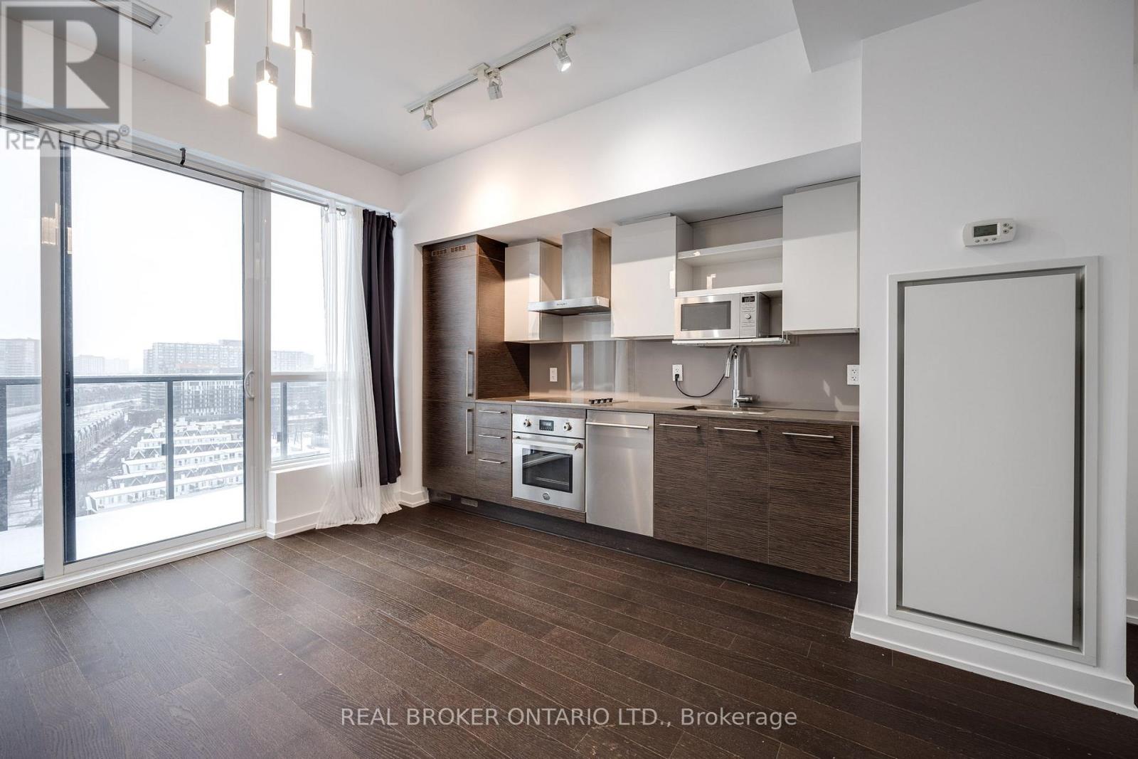 A modern kitchen with wooden floors and white cabinetry.