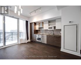 A modern kitchen with wooden floors and white cabinetry.