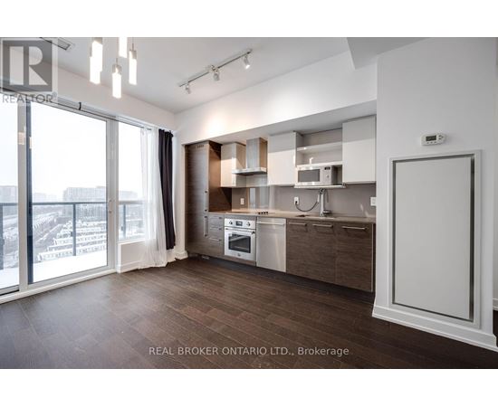 A modern kitchen with wooden floors and white cabinetry.