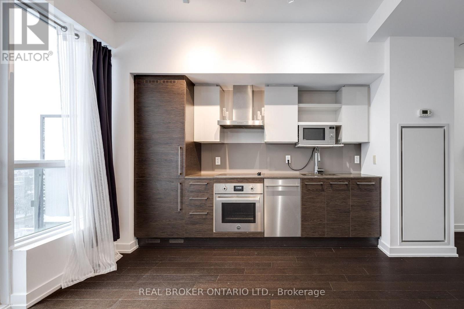 A modern kitchen with dark wood cabinets and stainless steel appliances.