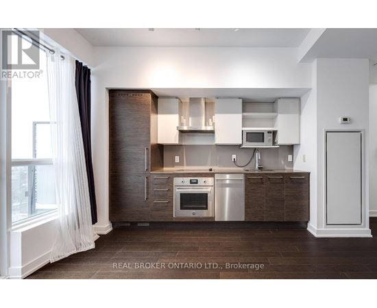 A modern kitchen with dark wood cabinets and stainless steel appliances.