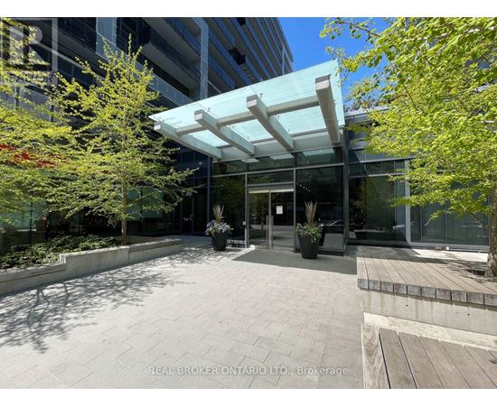 The image shows a modern building entrance with a glass wall and a white awning.
