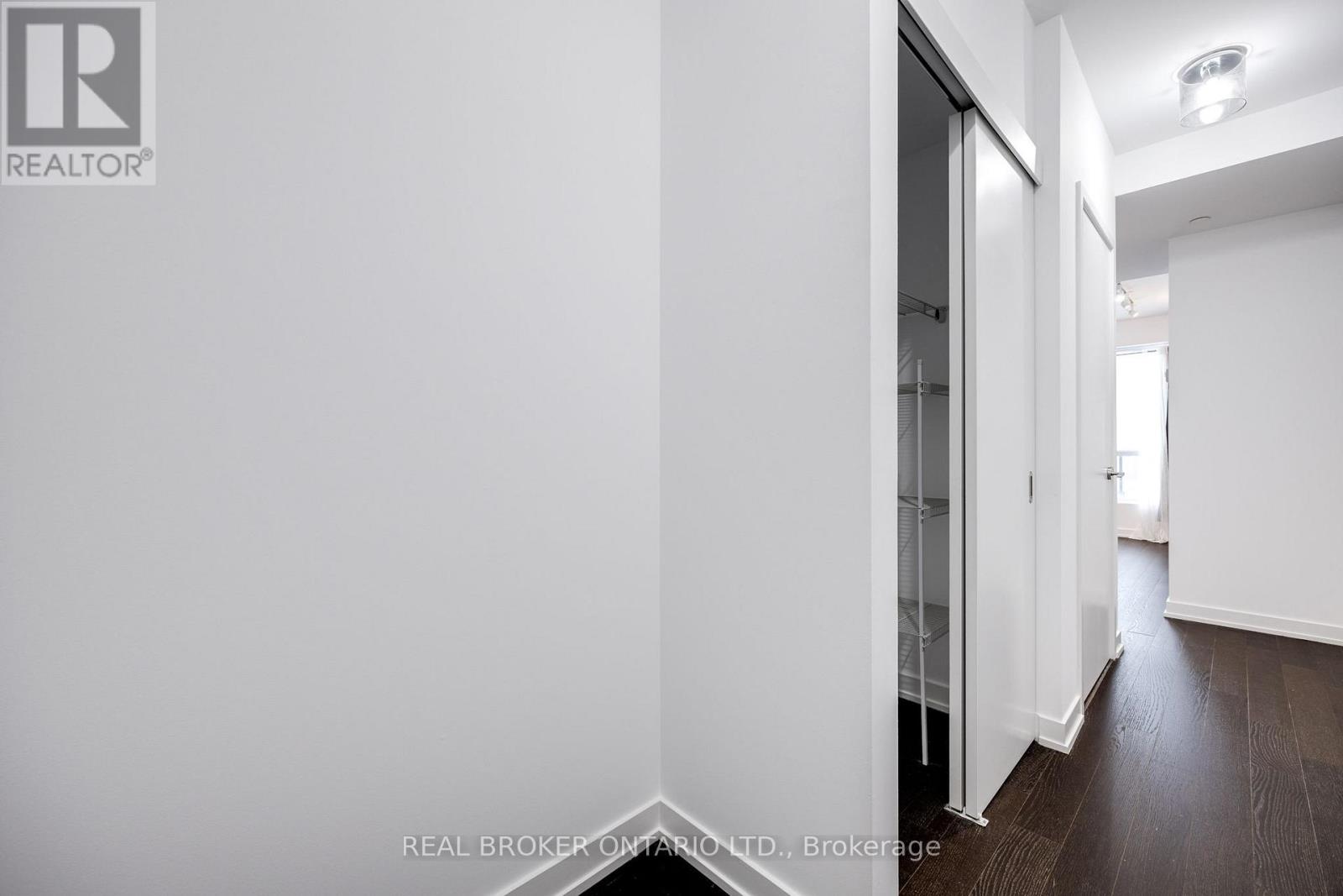 A hallway with a white wall and a glass door.