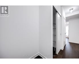 A hallway with a white wall and a glass door.