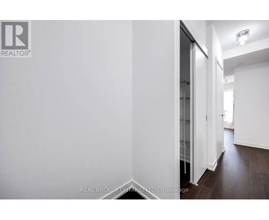 A hallway with a white wall and a glass door.