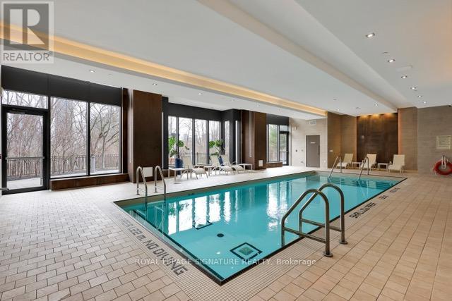 A large indoor swimming pool with a tiled floor and a glass wall.