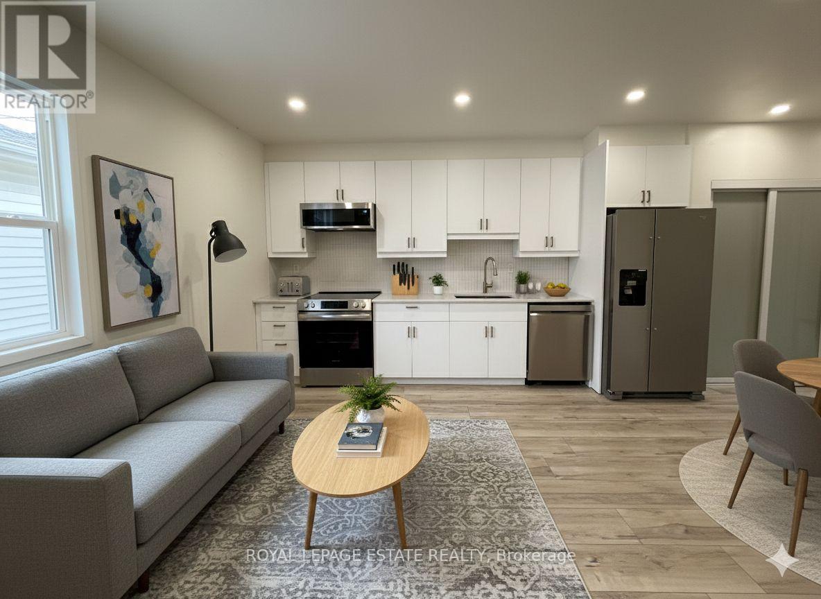 A well-lit, modern kitchen and living room with a grey sofa and wooden coffee table.