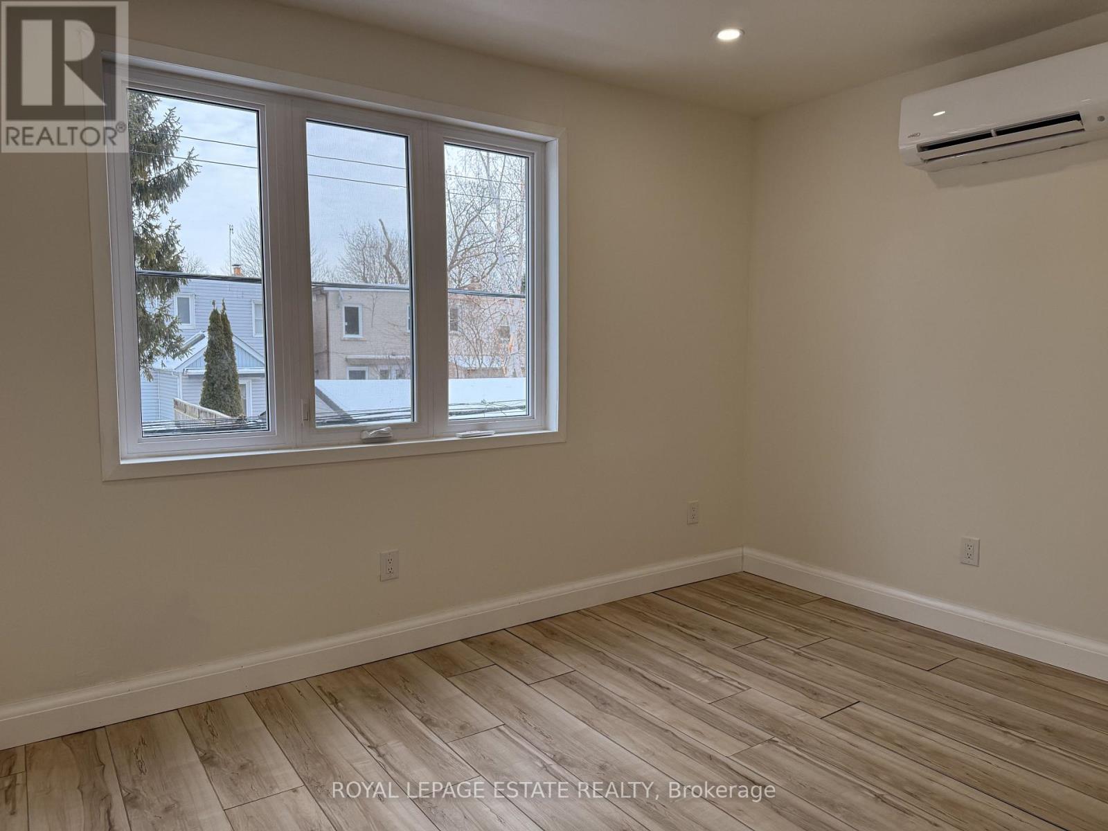 A room with a window showing a view of houses and trees outside.