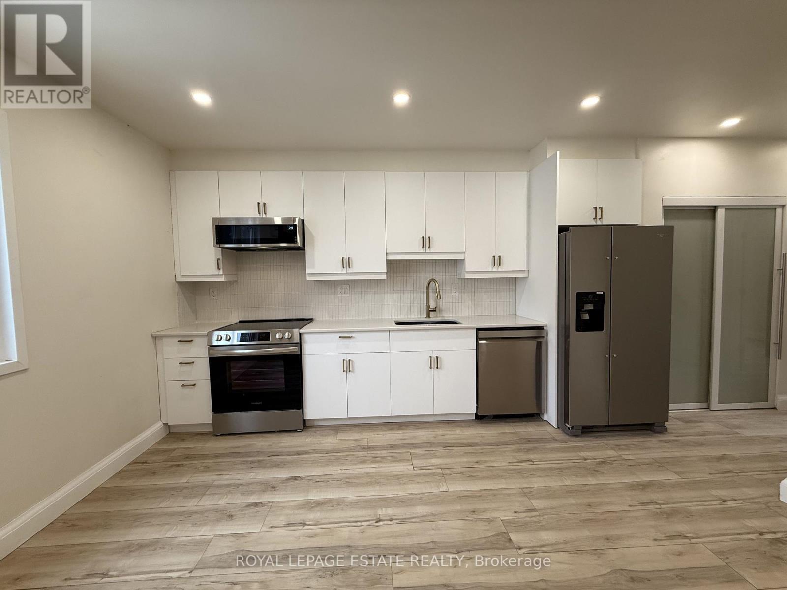 A kitchen with white cabinets and a wooden floor.