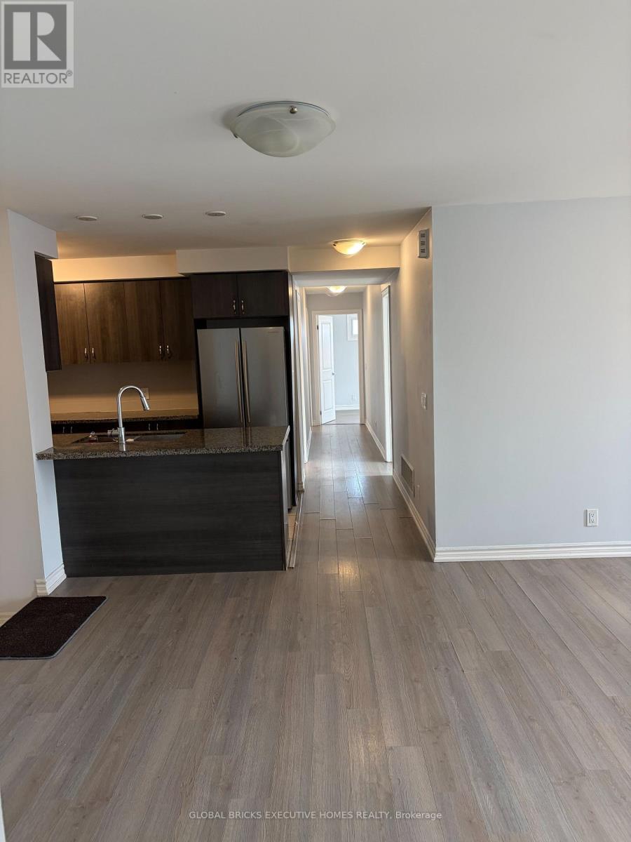 A spacious kitchen with dark wood cabinets and a white fridge.