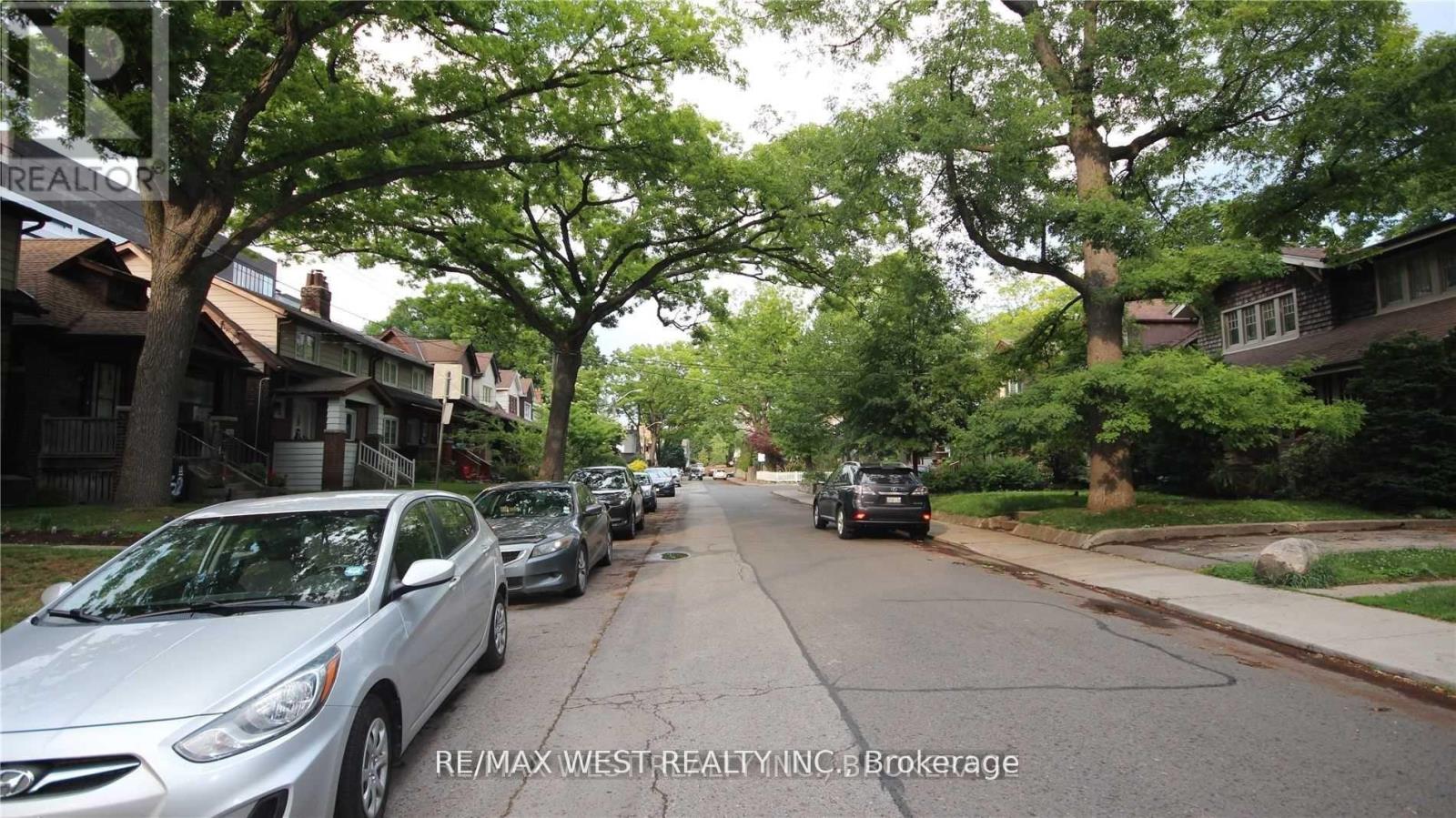 A street with parked cars and houses on both sides.