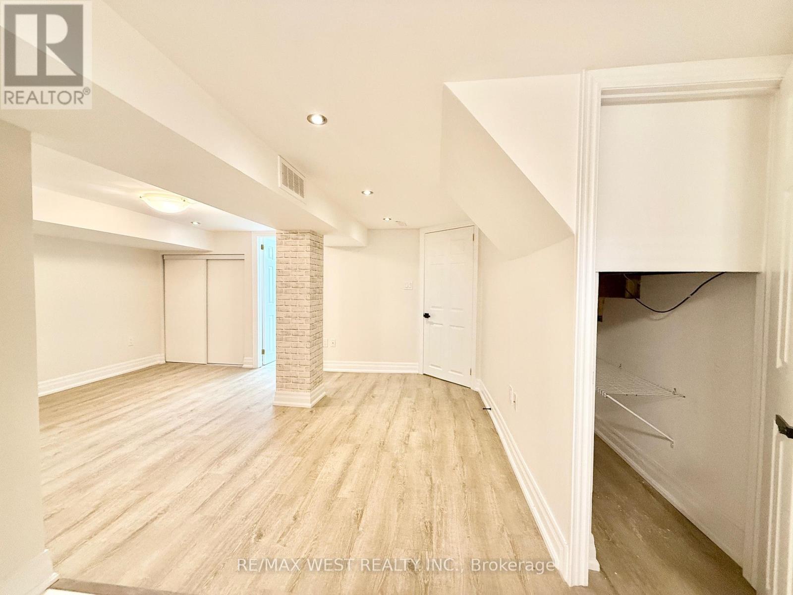 A spacious room with wooden flooring and white walls.