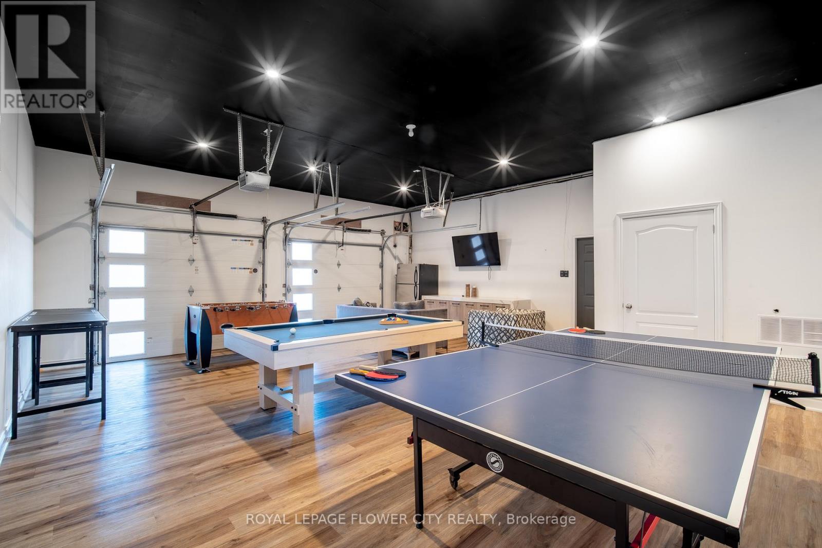 A pool table and ping pong table in a room with a black ceiling.