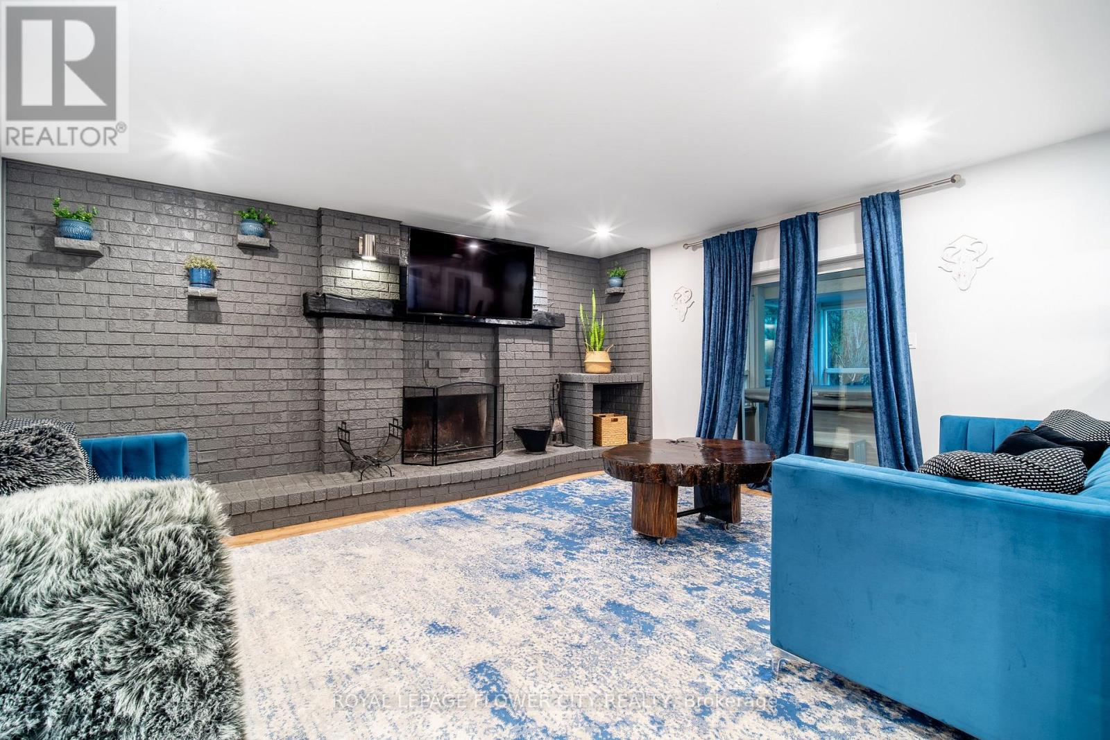 A blue couch sits in a living room with a fireplace and a television.