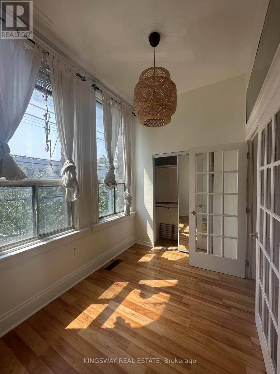 A room with wooden floors and white walls, with a doorway leading to another room.