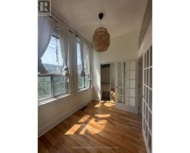 A room with wooden floors and white walls, with a doorway leading to another room.