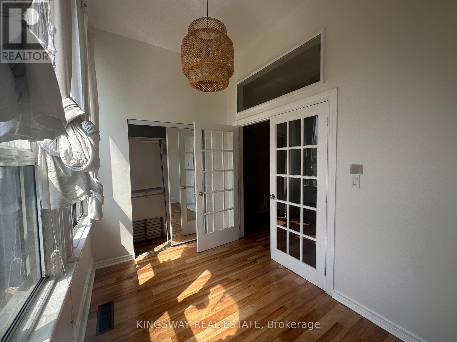 A room with a wooden floor and white walls, with a door and a window.