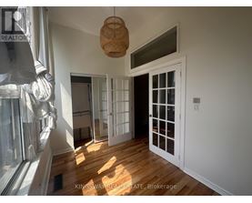A room with a wooden floor and white walls, with a door and a window.
