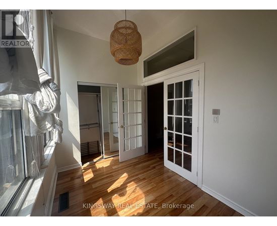 A room with a wooden floor and white walls, with a door and a window.