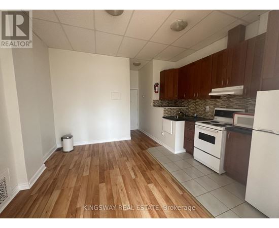 A kitchen with white appliances and wooden floors.