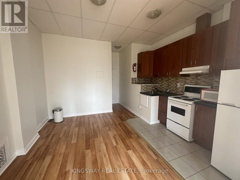 A kitchen with white appliances and wooden floors.