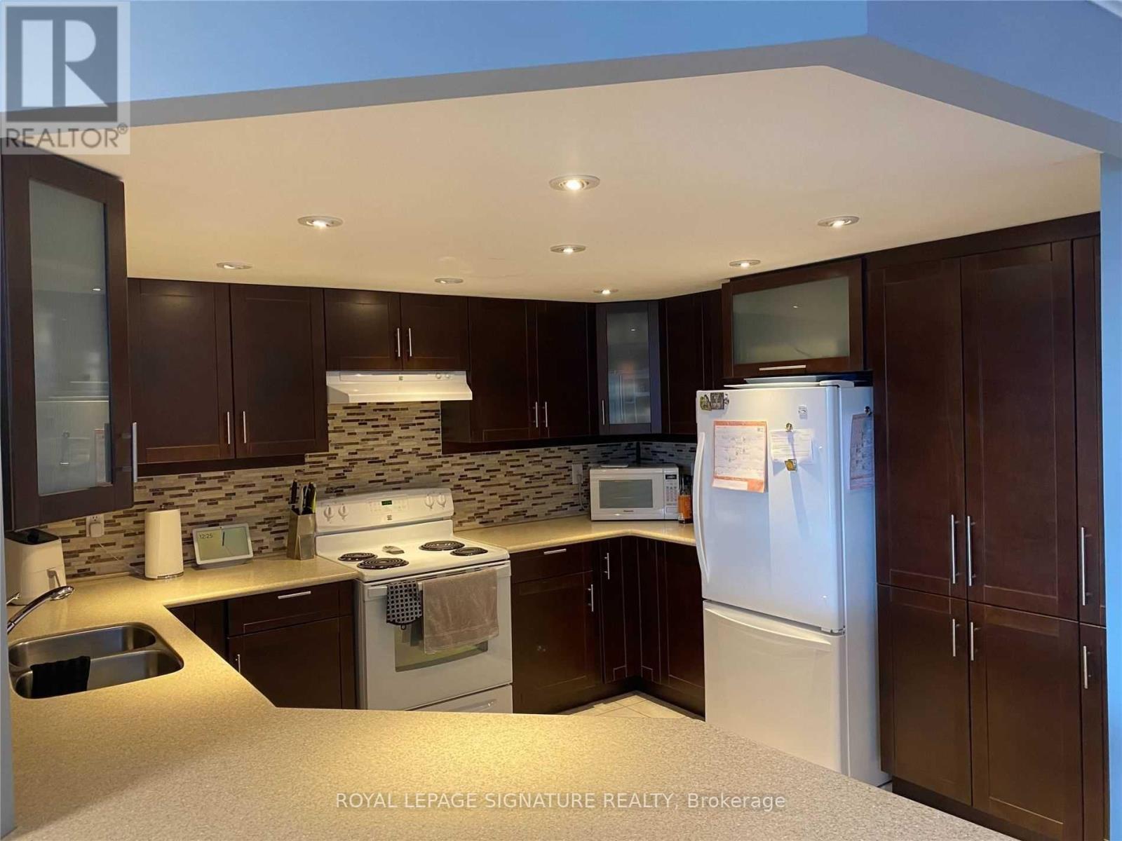 A kitchen with brown cabinets and a white fridge.