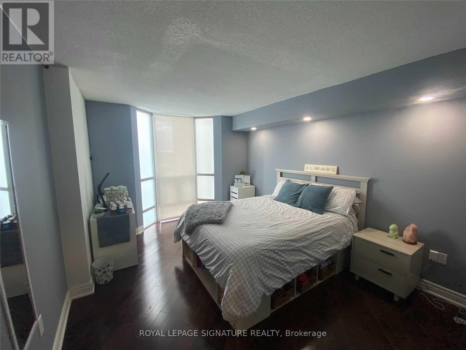 A bedroom with a bed, nightstand, and window.