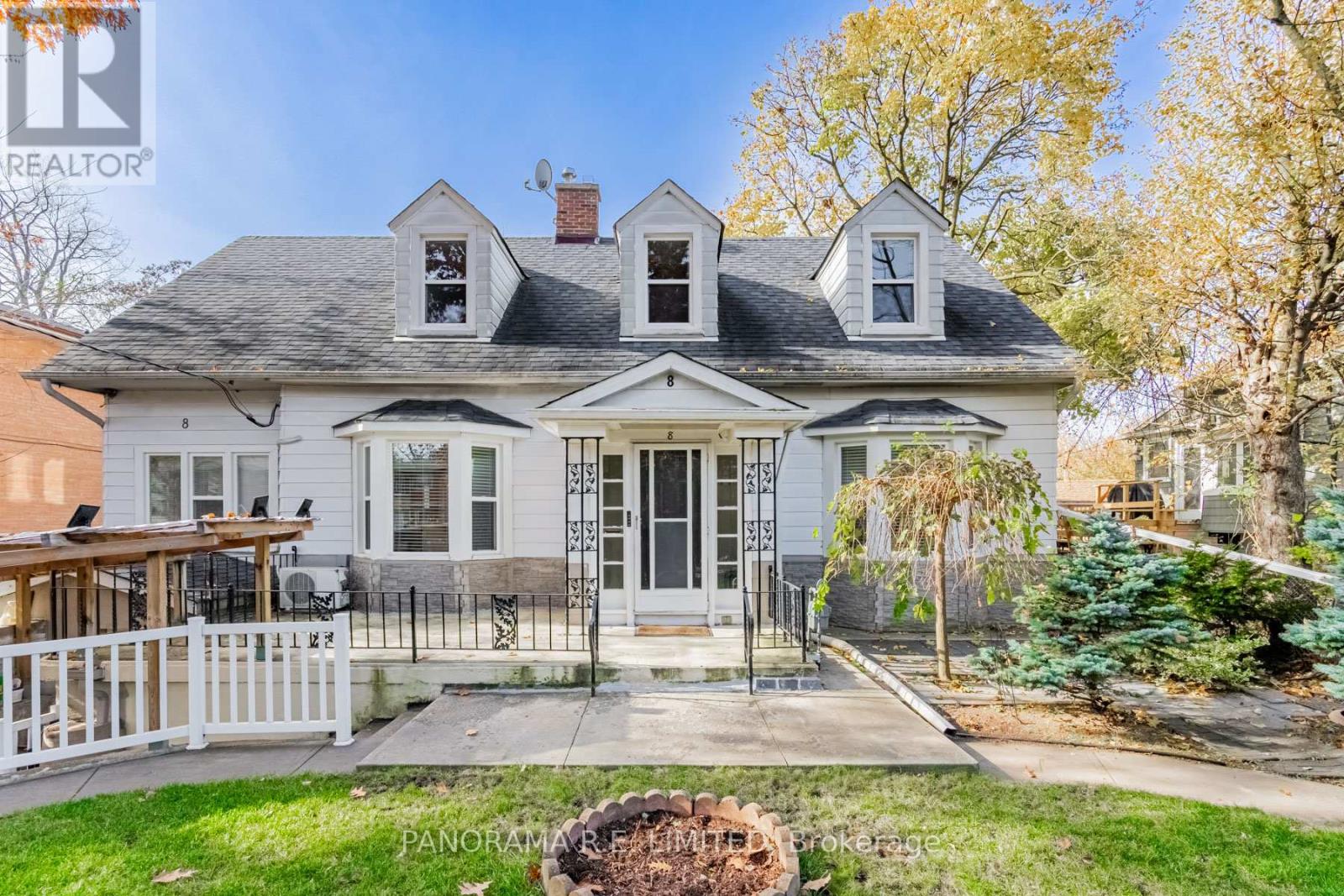 A white house with a black roof and a porch with a white railing.