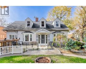 A white house with a black roof and a porch with a white railing.