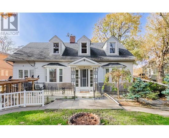 A white house with a black roof and a porch with a white railing.