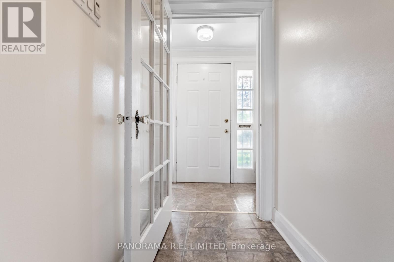 A hallway with a white door and a white wall.