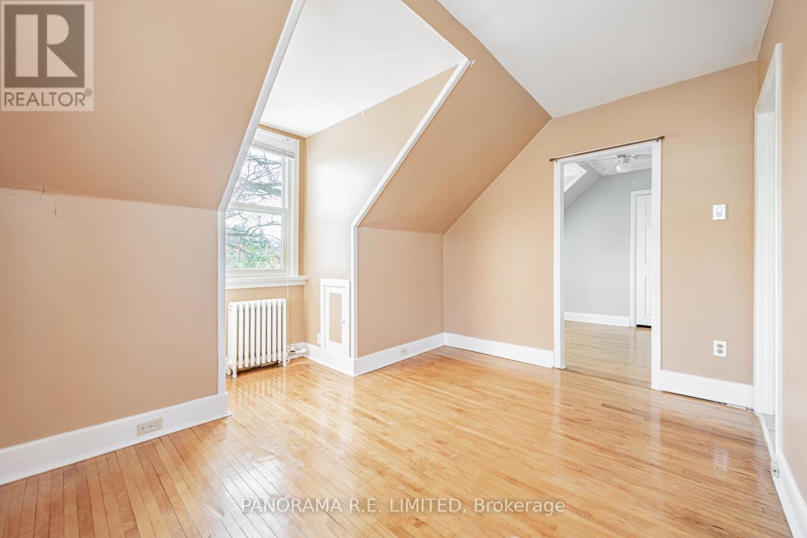 A room with wooden floors and a window with a view of trees.