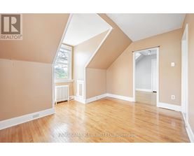 A room with wooden floors and a window with a view of trees.