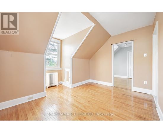 A room with wooden floors and a window with a view of trees.
