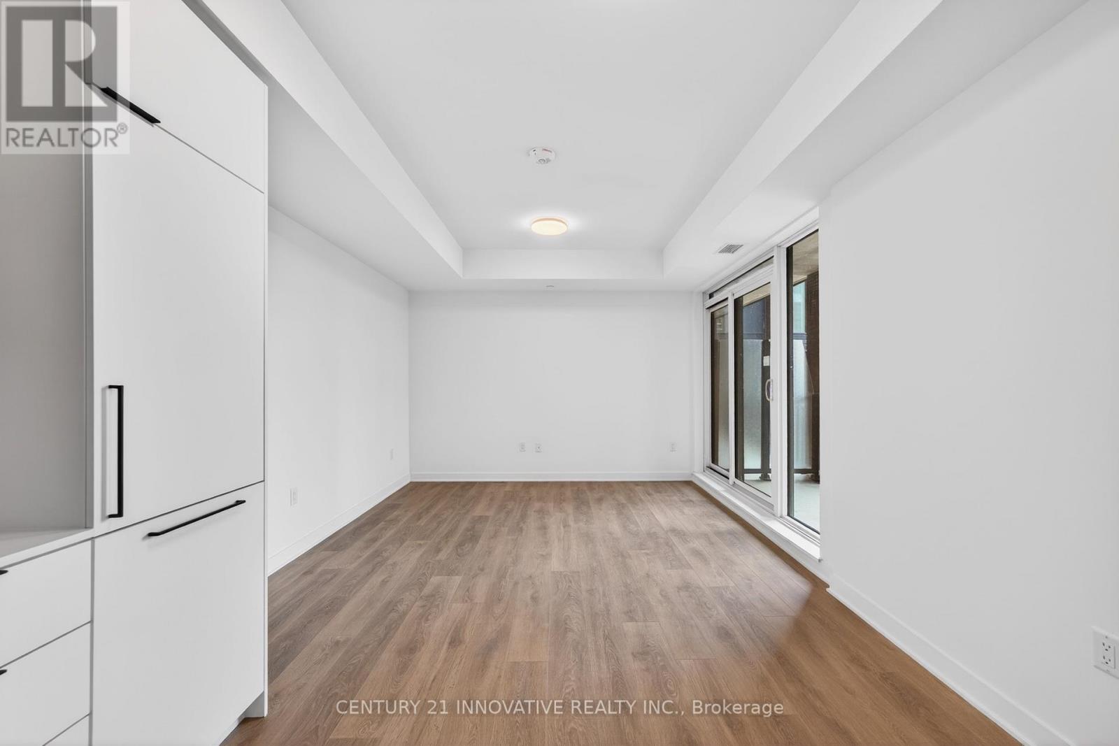 A spacious room with wooden flooring and white walls.