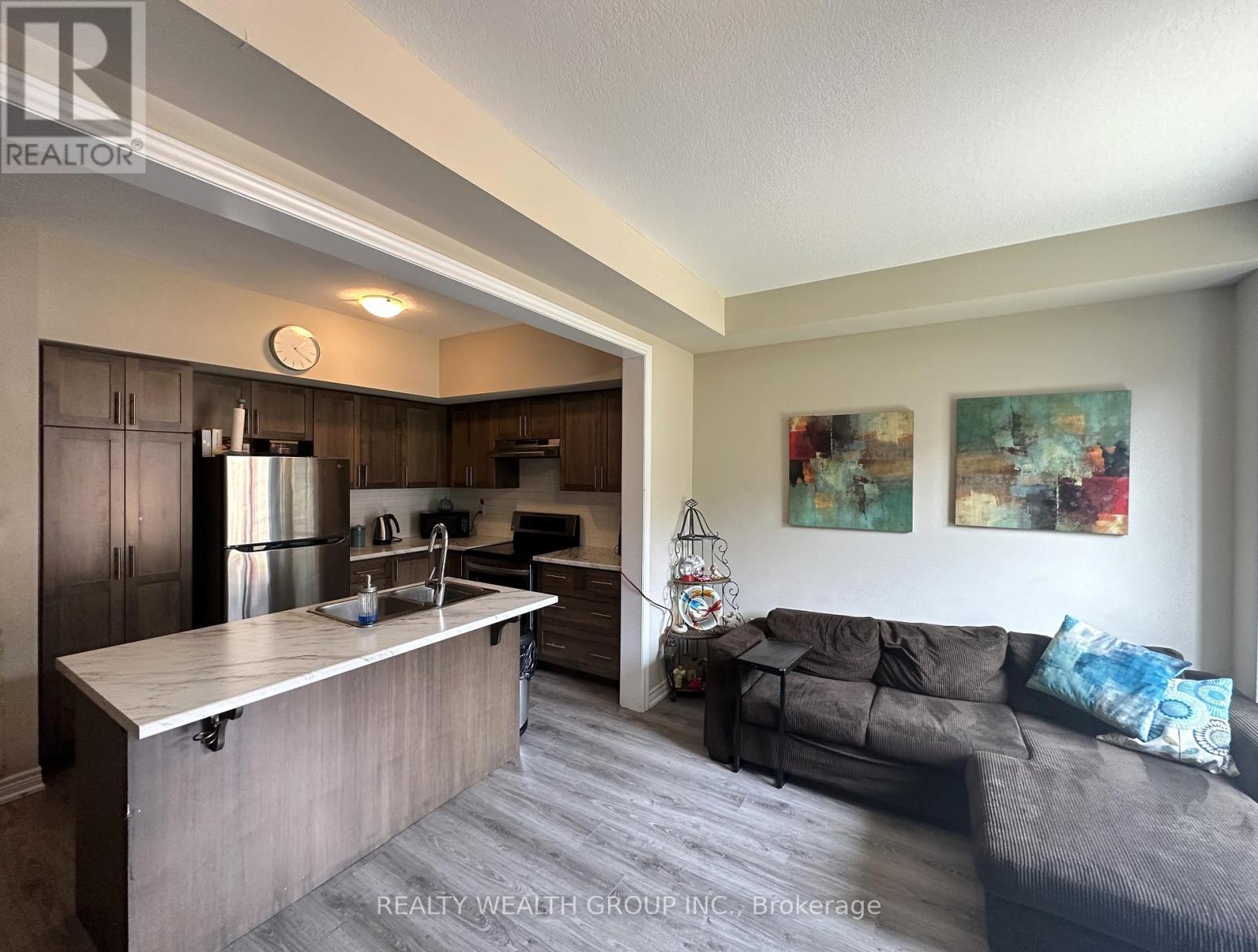 A kitchen with a refrigerator, sink, and cabinets is shown.