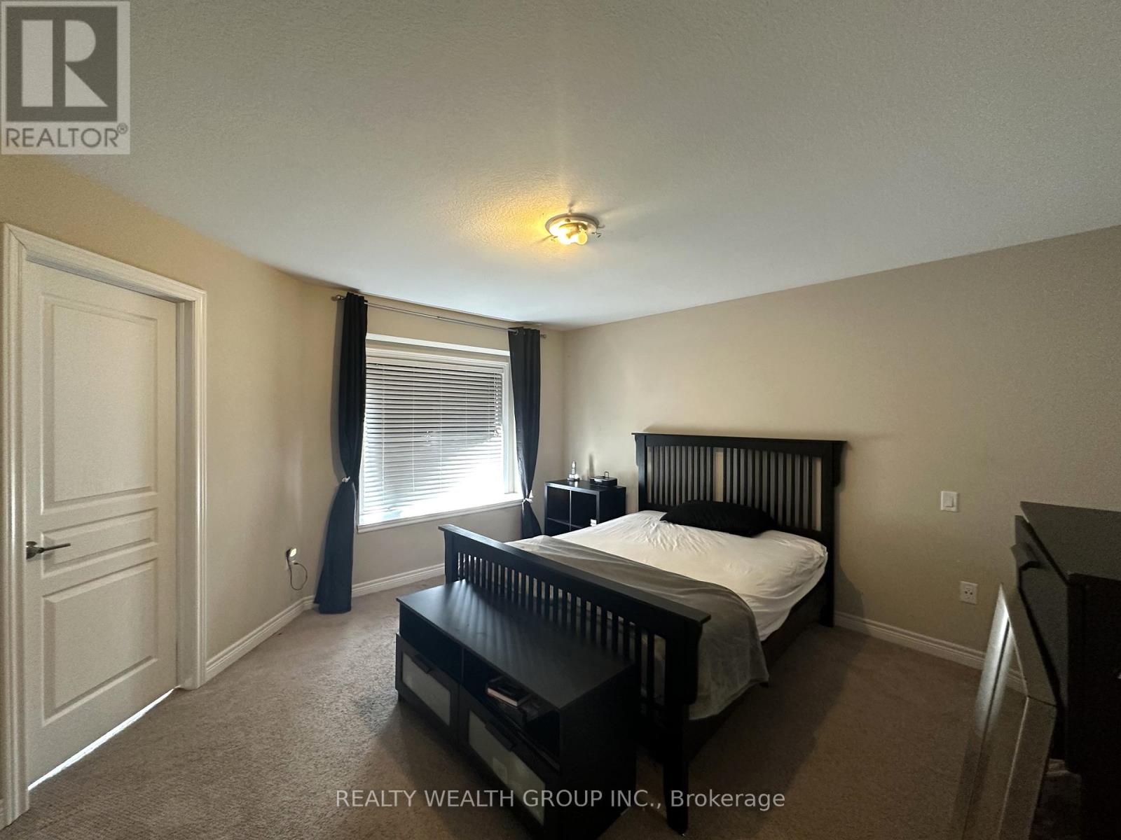 A bedroom with a bed, nightstand, and window.