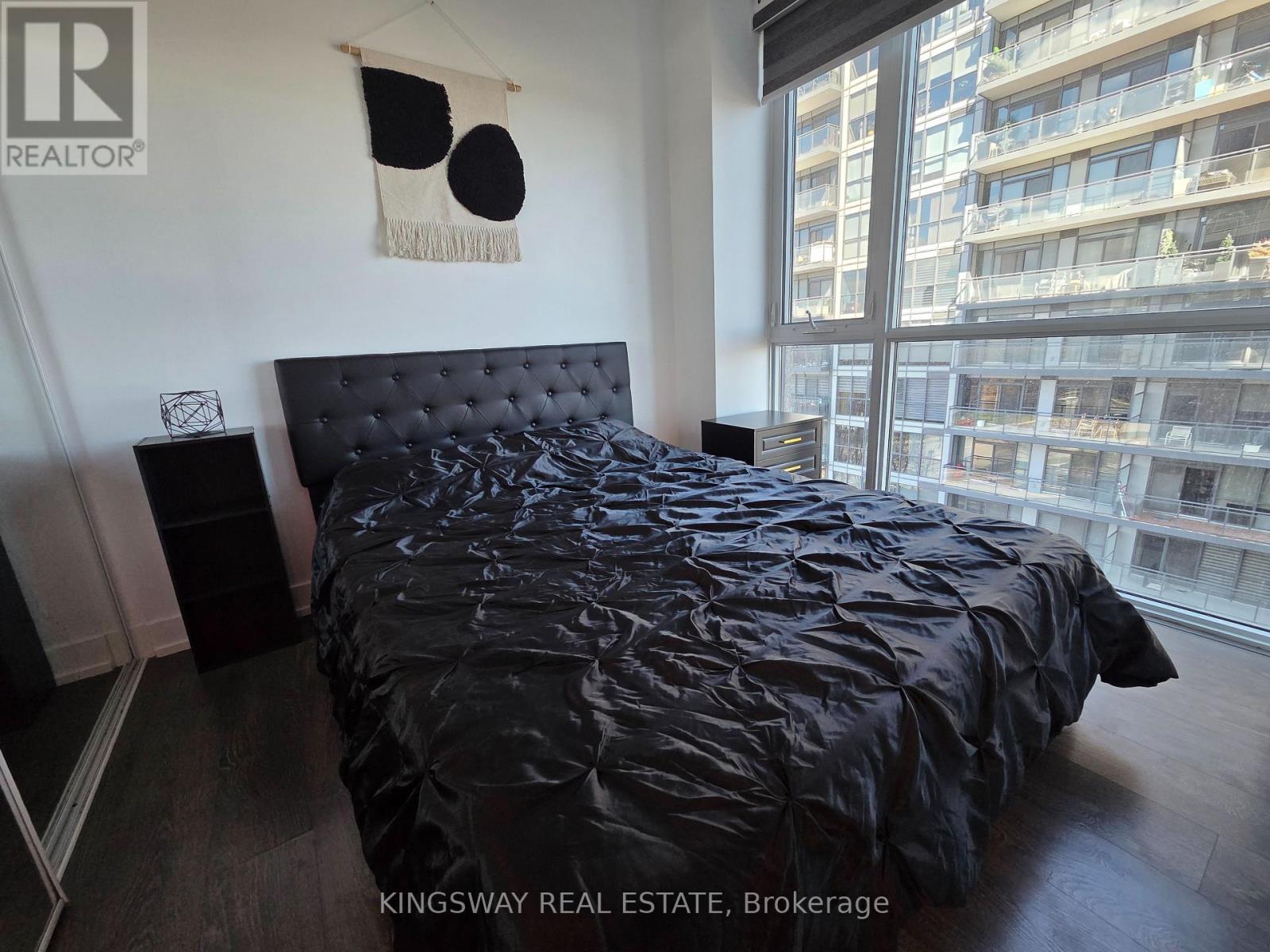 A bedroom with a black bedspread and a black headboard.