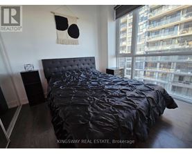 A bedroom with a black bedspread and a black headboard.