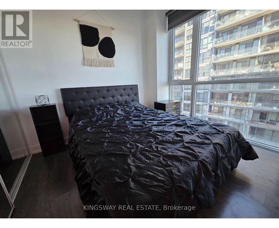 A bedroom with a black bedspread and a black headboard.