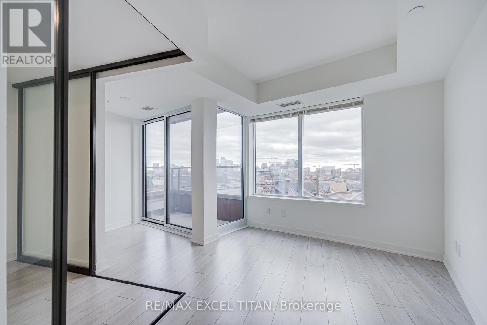 A spacious, empty room with a view of the city through large windows.