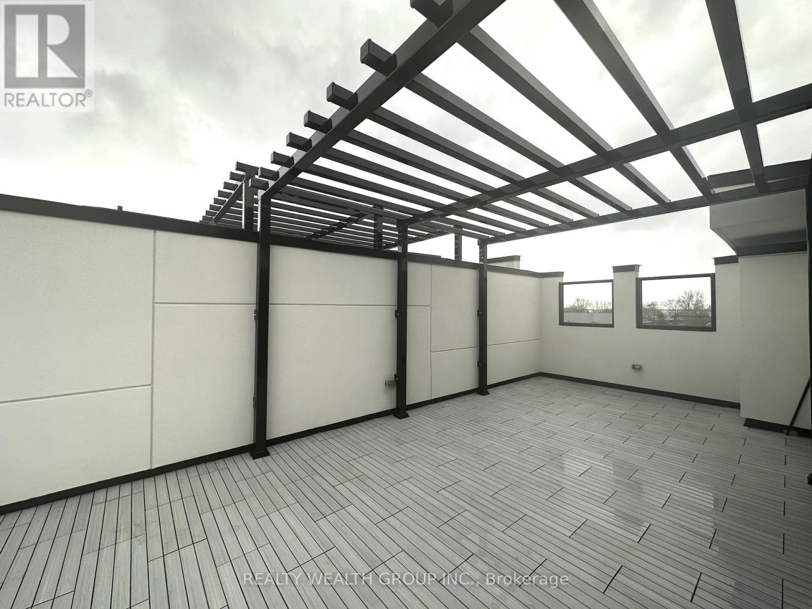 A spacious outdoor area with a wooden pergola and tiled flooring.