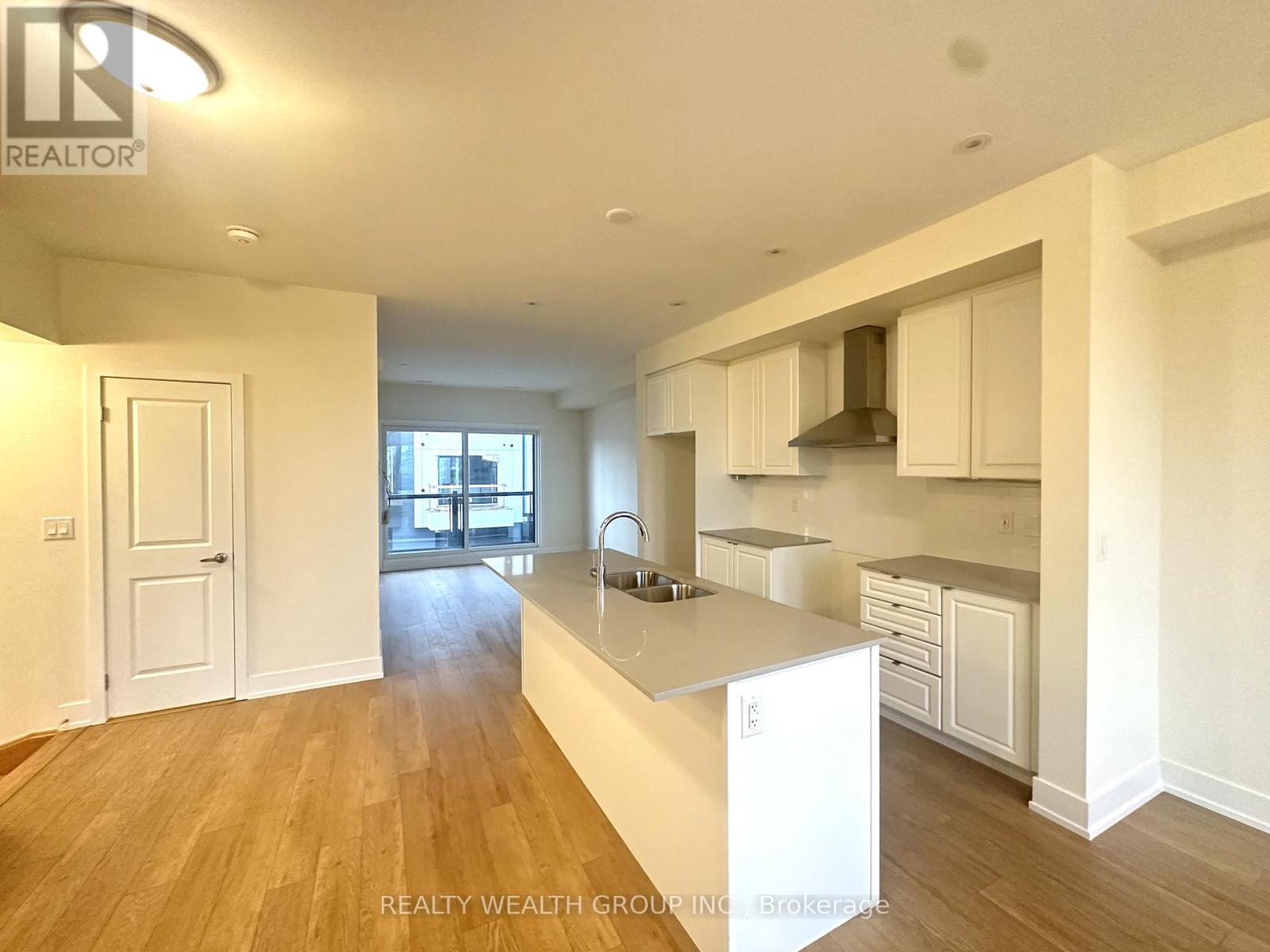 A spacious kitchen with white cabinets and a wooden floor.