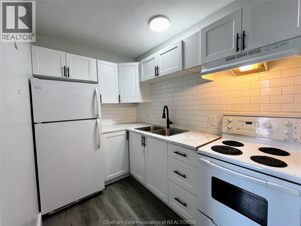 A white kitchen with a refrigerator, stove, and cabinets.