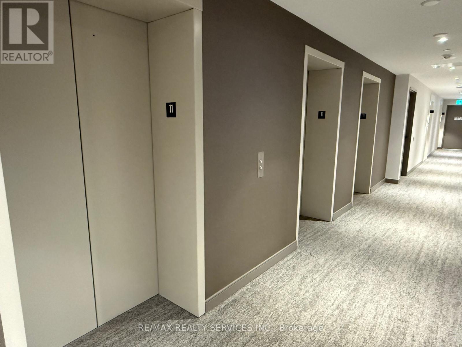A hallway with a carpeted floor and a series of doors on the left side.