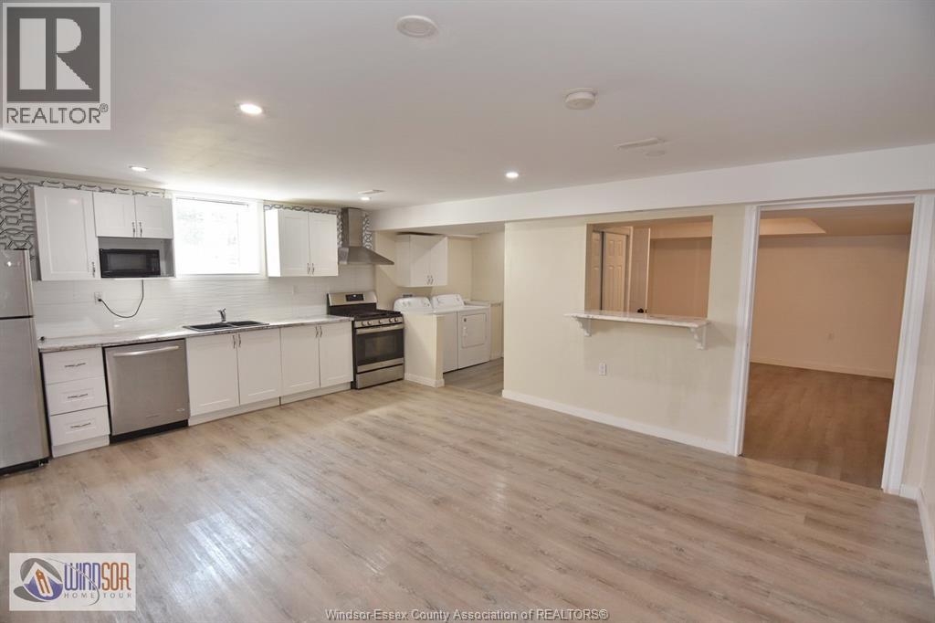 A spacious kitchen with white cabinets and a wooden floor.