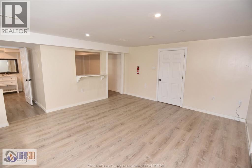 A spacious room with wooden flooring and white walls.