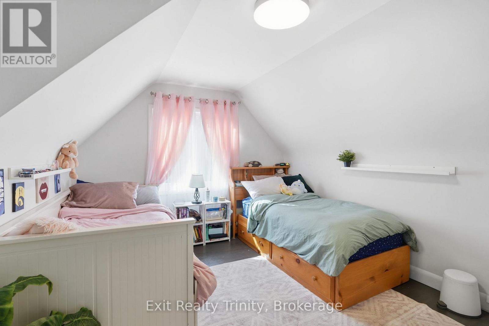 A bedroom with two beds and a window with curtains.